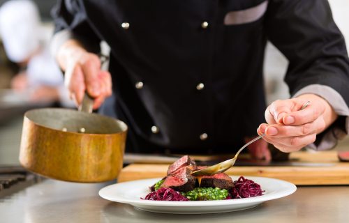 Chef in hotel or restaurant kitchen cooking, only hands, he is working on the sauce for the food as saucier, a Risotto